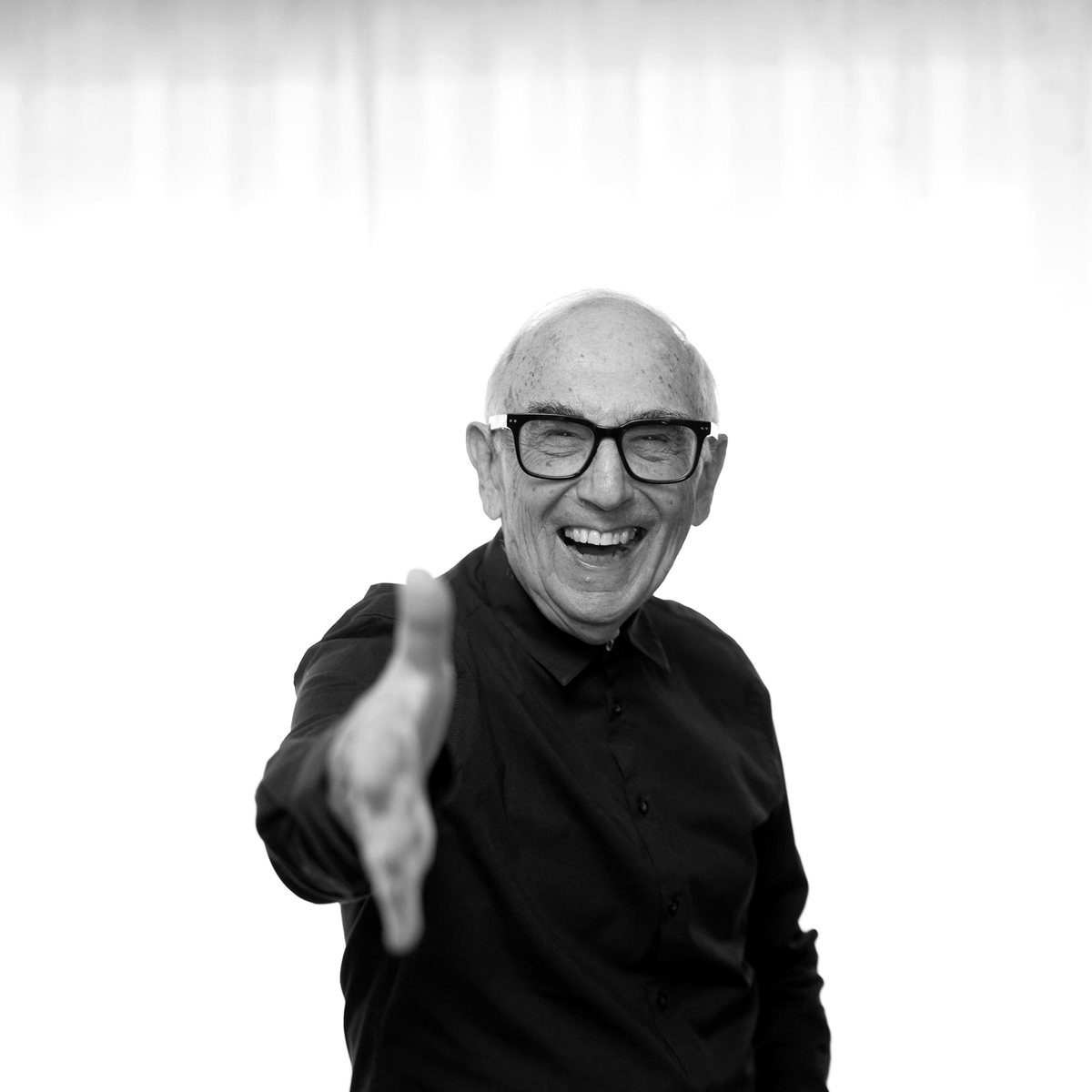 Mike Yershon laughing and reaching out a hand to shake, black and white