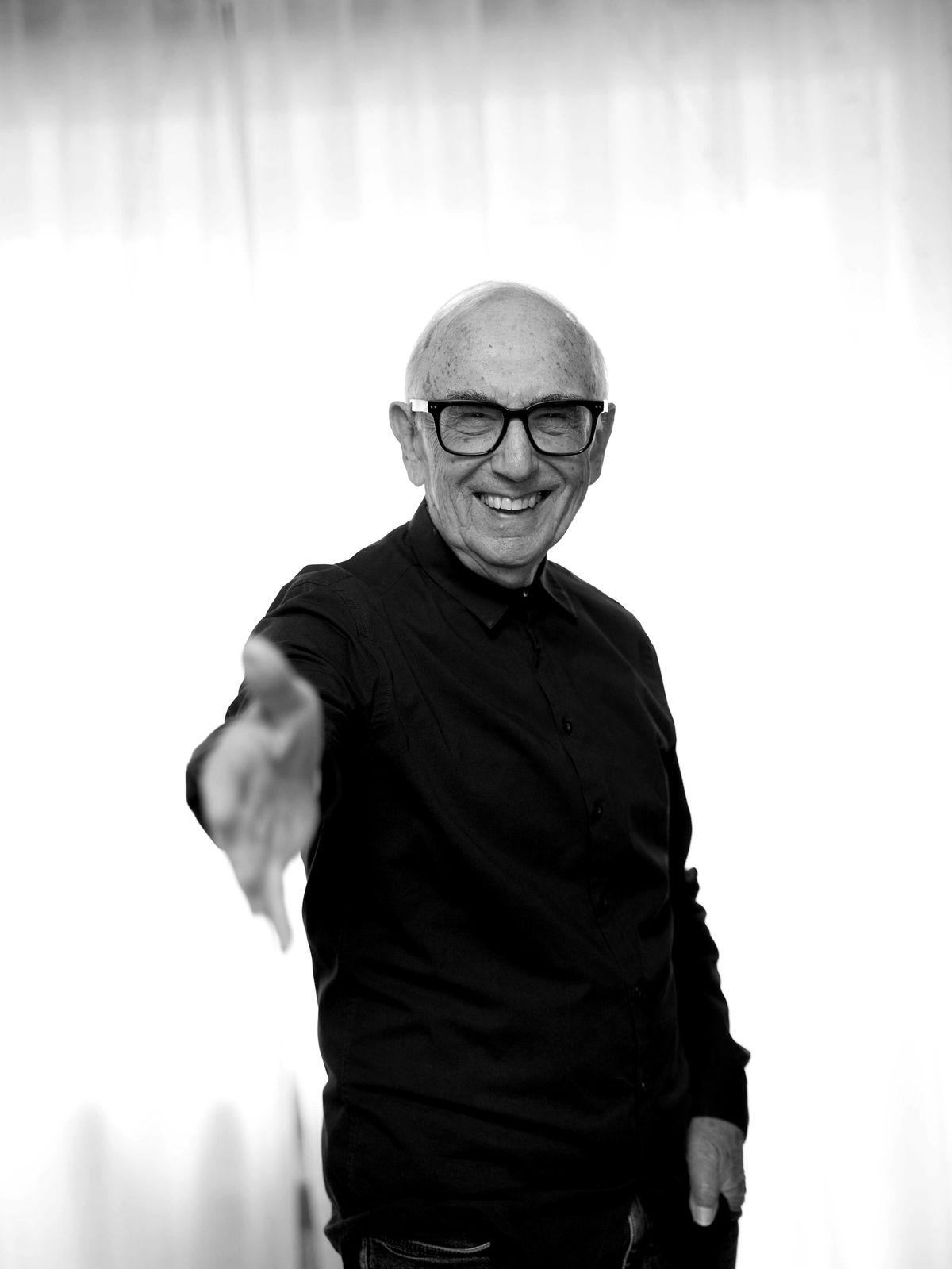Mike Yershon laughing and reaching out a hand to shake, black and white